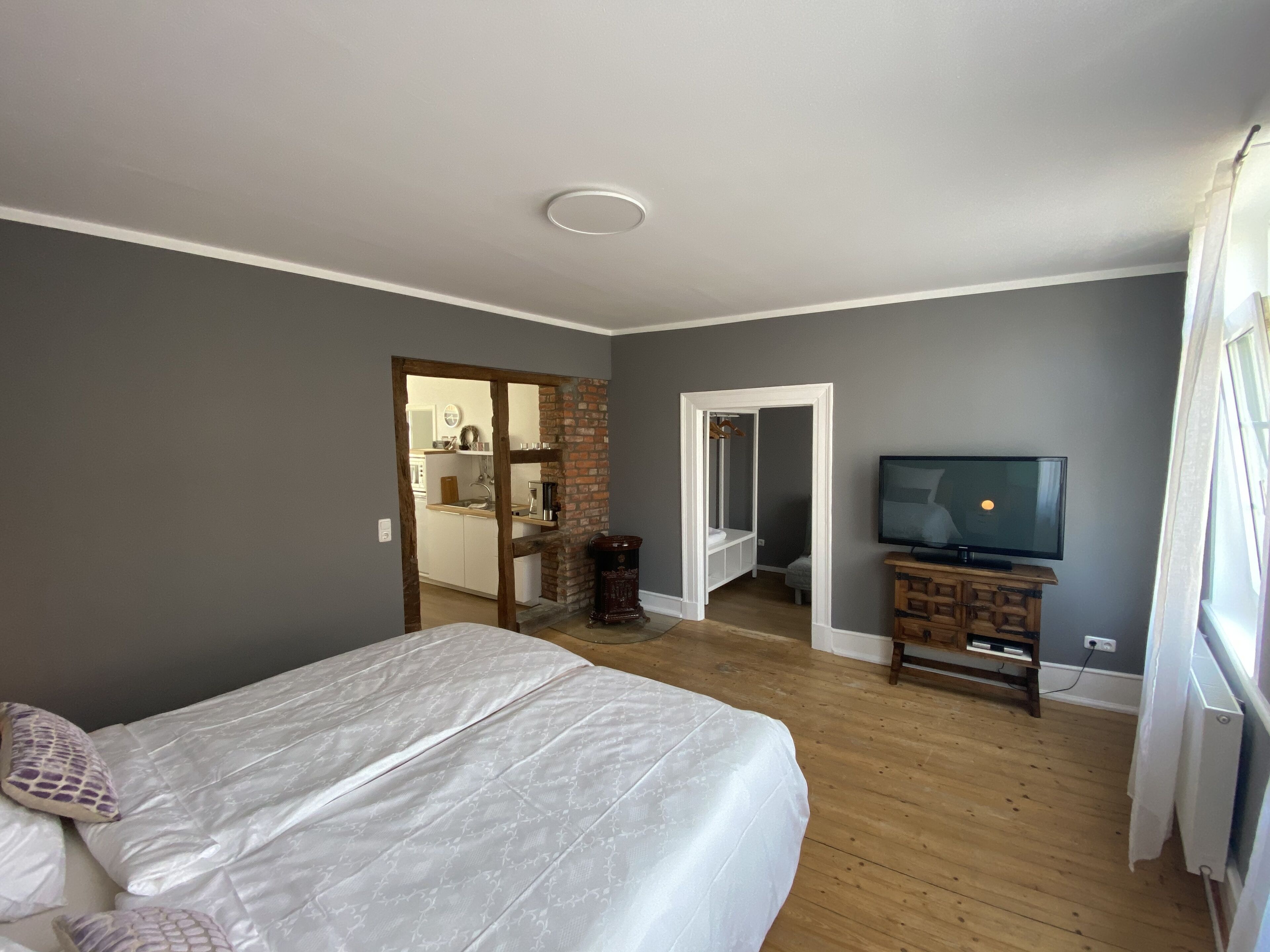 A bedroom with a bed, a television, and a dresser.