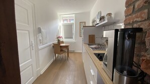 A kitchen with a wooden table, a refrigerator, and a brick wall. - Center, modern renovated old town apartment, Torster #3 (Hameln)