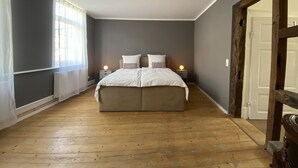 A bedroom with a large bed, two bedside tables with lamps, a radiator, and a wooden floor. - Center, modern renovated old town apartment, Torster #3 (Hameln)