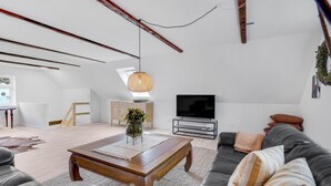 Ein geräumiges Wohnzimmer mit Couchtisch aus Holz, Ledersofa und Fernseher.