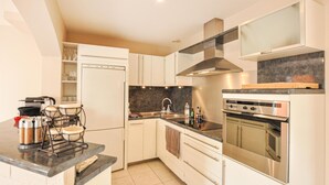 Een moderne keuken met witte kastjes, een oven van roestvrij staal en een zwart aanrecht.