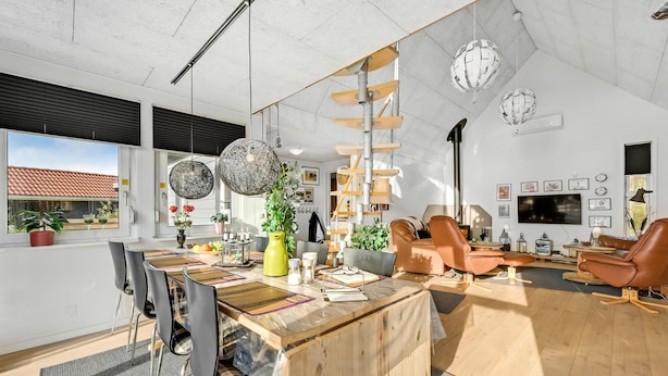 Ein modernes Wohnzimmer mit einem Holzespeisetisch, Ledersofas und einem an der Wand befestigten Fernseher.