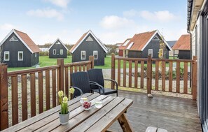 Enjoy a serene view of the surrounding landscape from this deck, complete with a table for two and a refreshing drink.