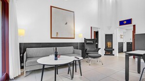 A modern hotel room with a grey sofa, a round table, a fireplace, and a large abstract painting on the wall. - Amazing home in Grenaa with kitchen (Grenaa)