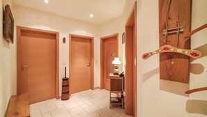 Un corridoio con porte in legno, un piccolo tavolo con una lampada e un appendiabiti in legno con un appendino decorativo.