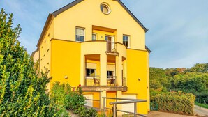 Un edificio giallo con un balcone, diverse finestre e una piccola finestra circolare in cima.