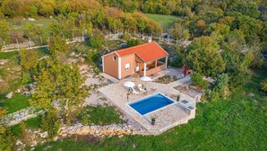 Ein Haus mit Swimmingpool, umgeben von Bäumen und einem Kiesweg.