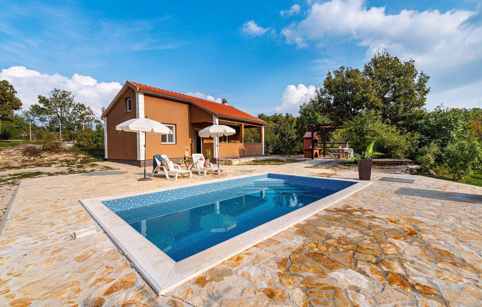 A house with a swimming pool, outdoor seating, and a garden.