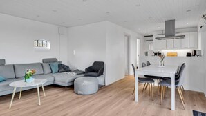 A modern living room with a grey sofa, a round coffee table, and a dining area with a white table and chairs. - Cozy home in Hadsund with WiFi (Hadsund)