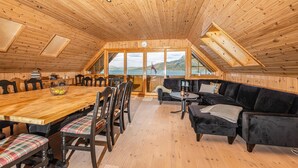 A wooden cabin with a dining area, a sofa, and a view of the lake.