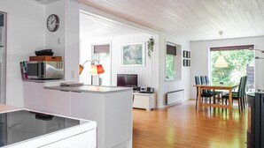 A modern kitchen with a microwave, a coffee maker, and a dining area with a table and chairs. - 3 bedroom lovely home in Rønne (Rønne)
