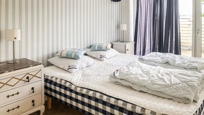 Ein ordentlich bezogenes Bett mit einer karierten Tagesdecke, zwei Kissen und einem Nachttisch mit einer Lampe.