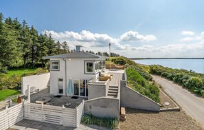 Una casa moderna con un patio, vistas al lago y un camino que lleva al agua.