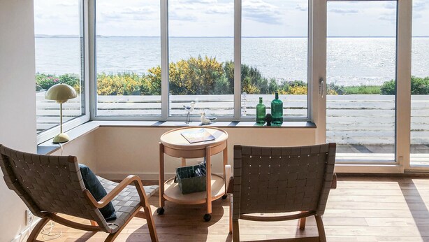 Ein Zimmer mit Meerblick, ein Tisch mit Stühlen und ein Fenster zum Meer.
