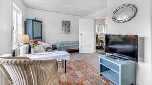 Et soveværelse med seng, et bord med lampe, et fjernsyn og et spejl på væggen.