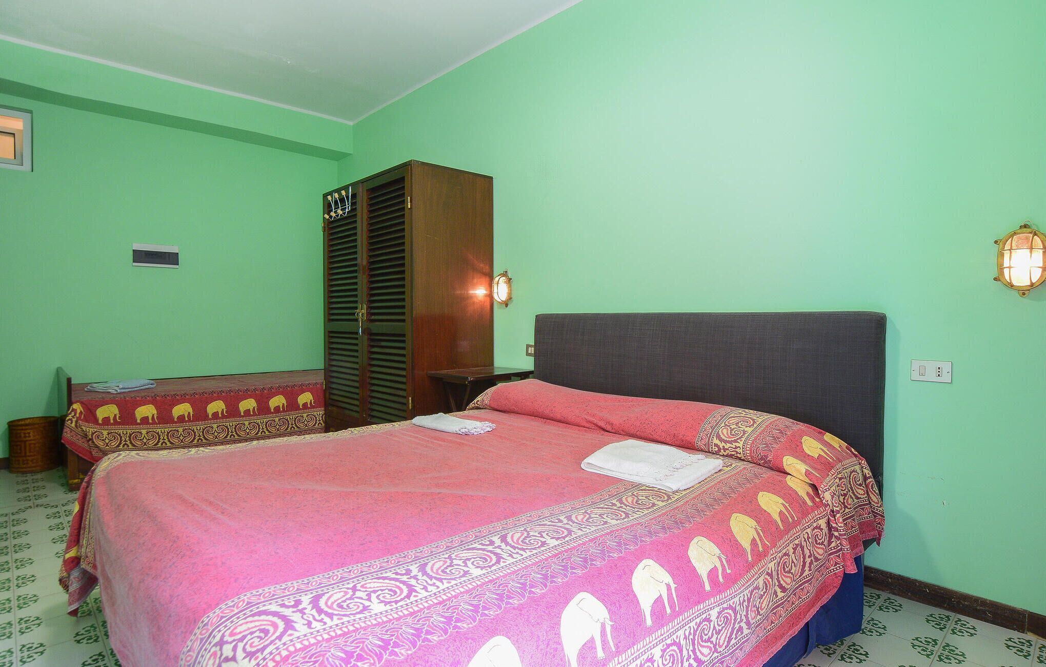 A room with two beds, a wardrobe, and a nightstand.