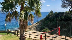 A coastal view with a palm tree, a red rope barrier, and a rocky cliff. - 3 bedroom nice apartment in Rio Marina (Rio Marina)