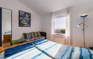 A bedroom with a bed, a desk, a chair, a window with a view, and a painting on the wall. - Nice apartment in Barbariga with WiFi (Barbariga)