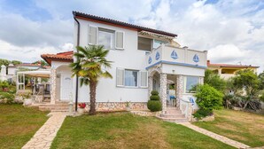 A two-story house with a stone facade, a covered patio, and a well-maintained lawn. - Nice apartment in Barbariga with WiFi (Barbariga)