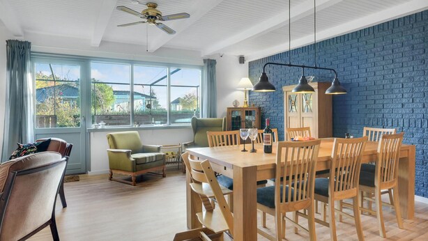 A dining area with a wooden table and chairs, a ceiling fan, and a view through large windows. - Gorgeous home in Grevinge with kitchen (Grevinge)