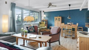 A cozy living room with a blue brick wall, wooden furniture, and a dining area with a wooden table and chairs. - Gorgeous home in Grevinge with kitchen (Grevinge)