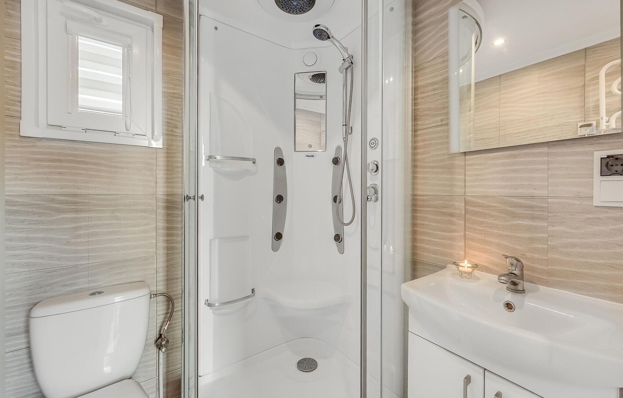 A modern bathroom with a glass-enclosed shower, a toilet, and a sink with a mirror above it.