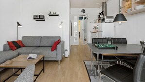 Een moderne woonkamer met een grijze bank, een houten salontafel en een eethoek met een tafel en stoelen.