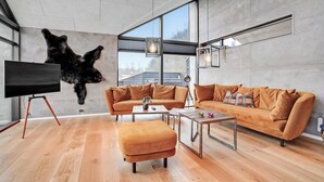 A modern living room with a large bear mounted on the wall, a sofa, a coffee table, and a TV on a tripod stand.