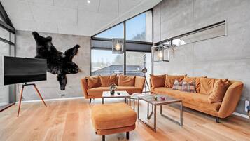 Un salon moderne avec une grande tête d’ours fixée au mur, un canapé, une table basse et un téléviseur posé sur un trépied.