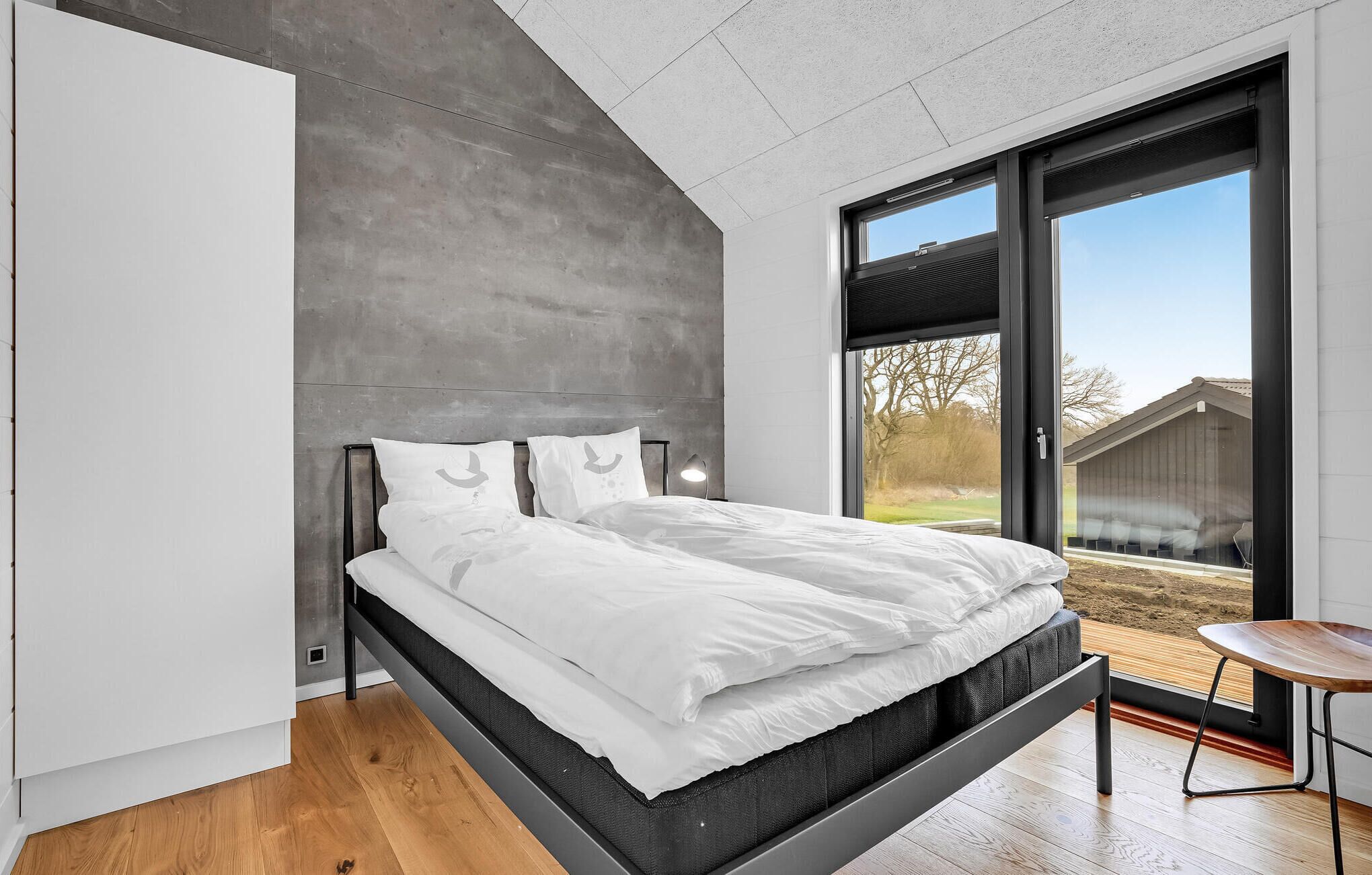 Une chambre moderne avec un lit, une table de chevet et une vue sur l’extérieur.