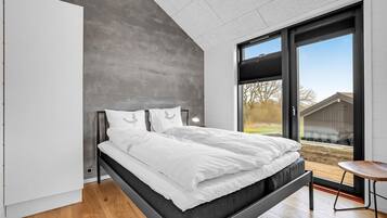 Une chambre moderne avec un lit, une table de chevet et une vue sur l’extérieur.
