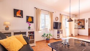 Una sala de estar con un sofá, una mesa de centro, un televisor y una estantería.