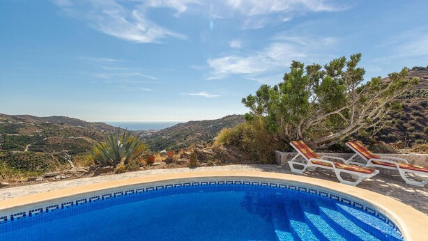 Una piscina con vistas a un paisaje montañoso y el mar al fondo.