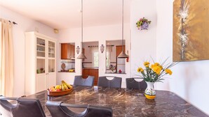 Una cocina moderna con armarios de madera, encimera de mármol y comedor con una mesa grande y sillas.