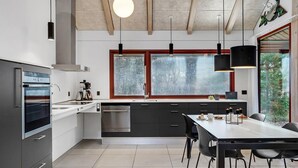 A modern kitchen with a built-in oven, a dishwasher, and a dining area with a table and chairs. - 2 bedroom amazing home in Grenaa (Grenaa)