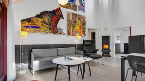 A modern living room with a grey sofa, two round tables, a fireplace, and abstract art on the walls. - 2 bedroom amazing home in Grenaa (Grenaa)