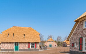 Traditional buildings with brick walls and thatched roofs, set amidst a serene open area.