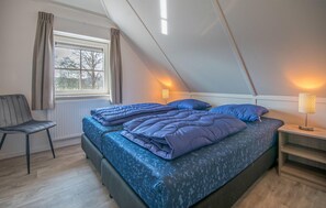Cozy retreat with a large bed, bedside tables, and a chair by the window, offering a view of the outdoors.