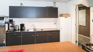 Een moderne keuken met donkere kastjes, een RVS spoelbak en een houten aanrechtblad.