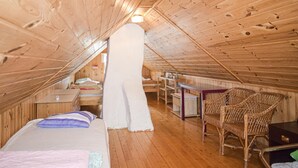 Une chambre mansardée chaleureuse avec un plafond en bois, un lit, une chaise et une petite table.