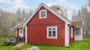 Une maison en bois rouge avec une porte et des fenêtres blanches, un petit porche et un drapeau.
