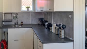 A compact kitchen with a sink, a coffee maker, a toaster, and a utensil holder.