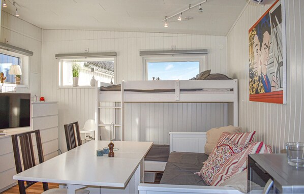 A compact, well-lit room with a bunk bed, a dining table, and a small kitchen area.