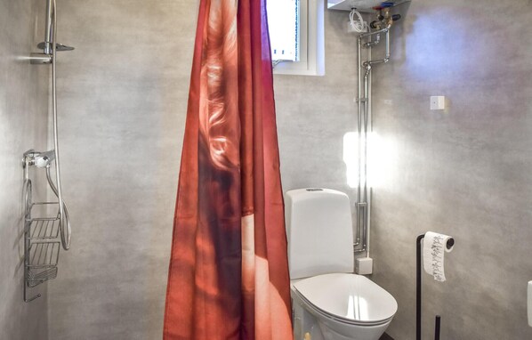 A bathroom with a shower, toilet, and towel rack.