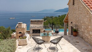 A stone building with a glass table and chairs overlooking a pool and the sea. - Gorgeous home in Blato (Blato)