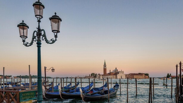 Gondolas docked at a pier with a historic building in the background.