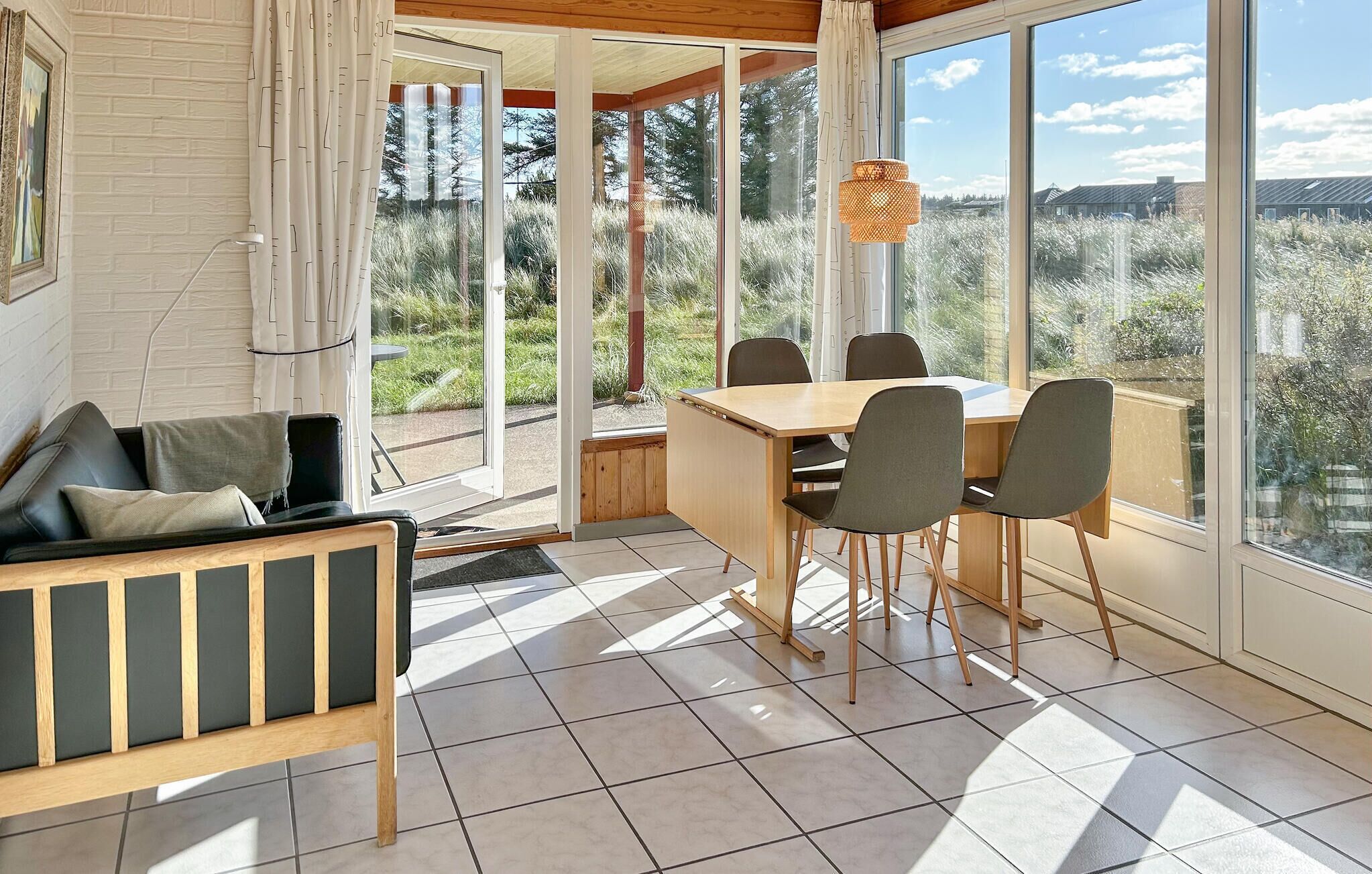 Un intérieur moderne comprenant un coin repas, un canapé et de grandes fenêtres donnant sur l’extérieur.