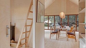 A modern interior with a dining area, wooden furniture, and a large window offering a view of the outdoors. - Nice home in Nexø with WiFi (Nexø)