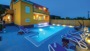 Un bâtiment à deux étages doté d’une piscine, d’un espace extérieur aménagé et d’une clôture en bois.