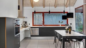 A modern kitchen with a large window, stainless steel appliances, and a dining area with a table and chairs. - Cozy home in Grenaa with kitchen (Grenaa)